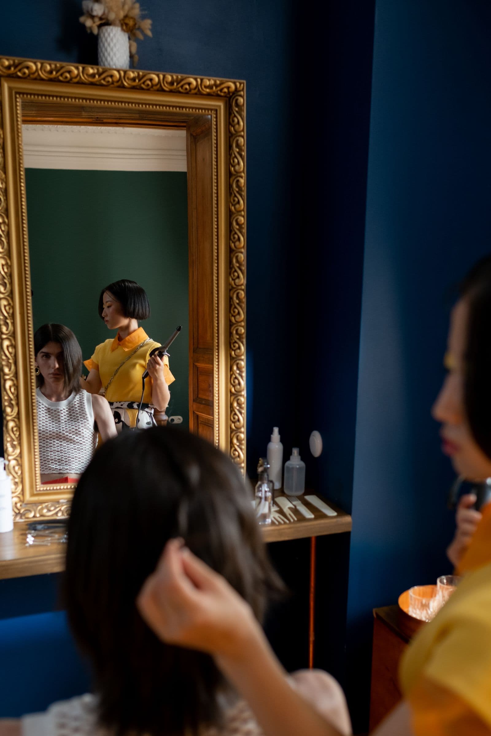 Estilista trabajando el cabello de una clienta frente al espejo